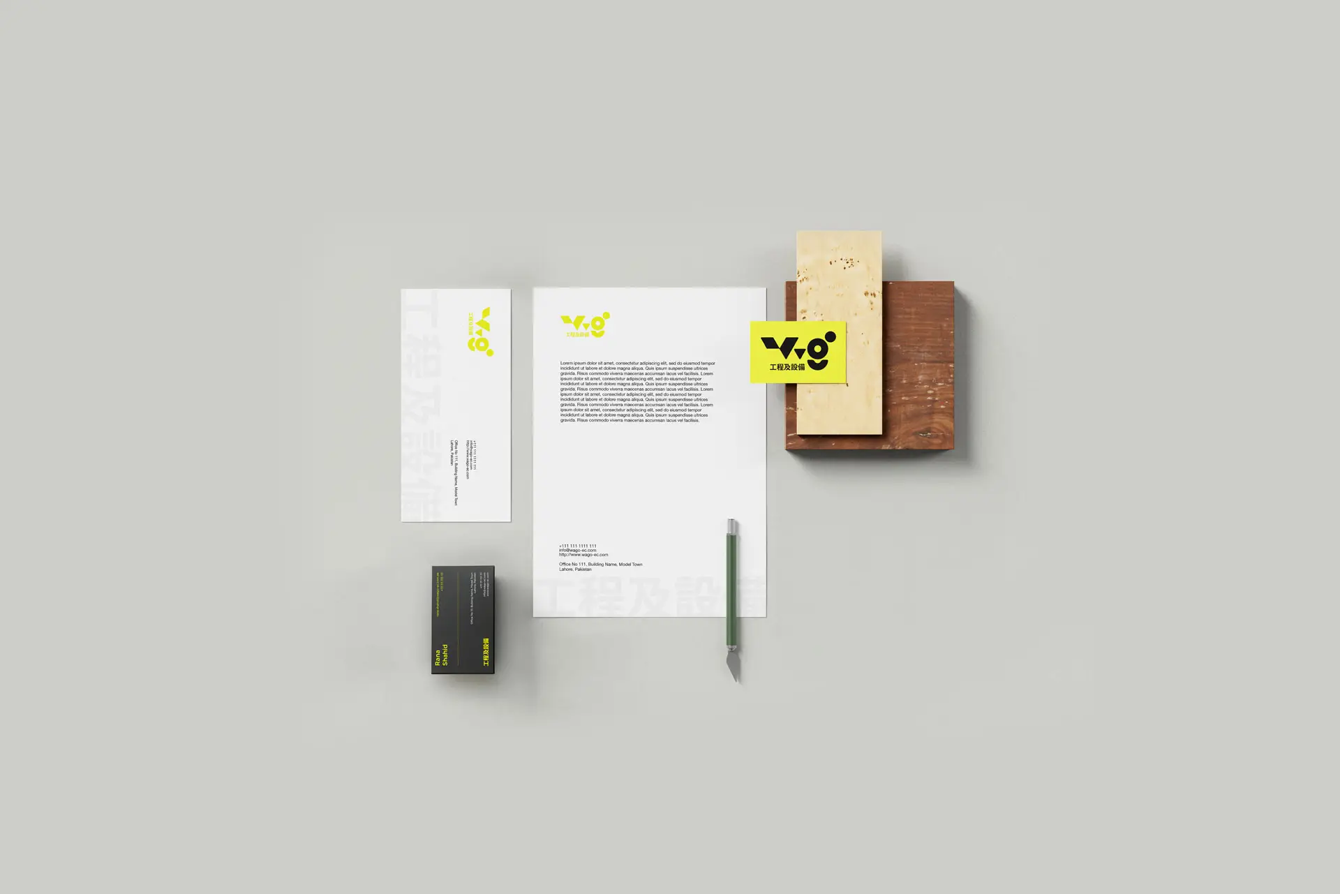 This image is a branding identity project. The stationery features a distinctive neon yellow color palette alongside dark grey accents. It is showcased as a mockup, featuring letterheads, business cards, and a pencil.